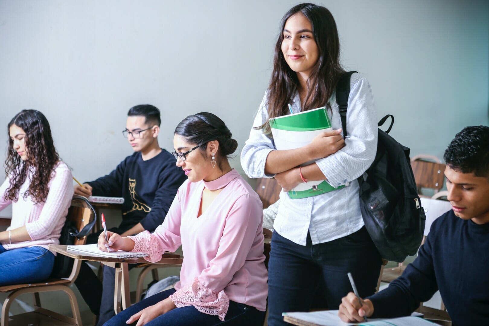 College students in a classroom with a female student standing